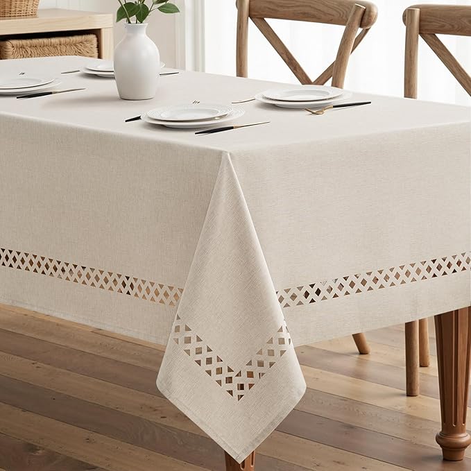 Beige rectangular linen-polyester blend tablecloth with decorative cutwork pattern, waterproof, stain-resistant, and shrink-resistant, measuring 52x70 inches.  Farmhouse style, suitable for dining rooms, weddings, parties, and outdoor picnics.