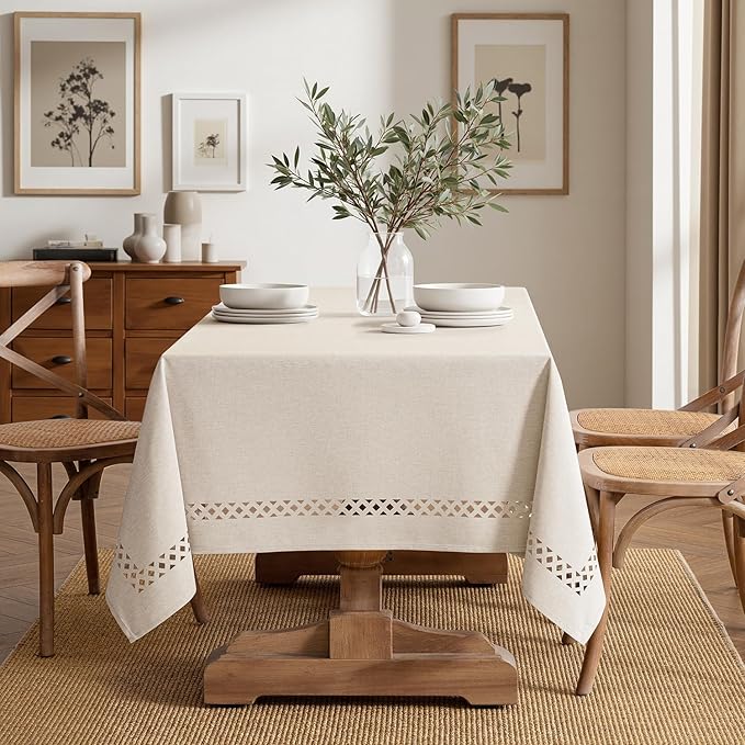 Beige rectangular linen-polyester blend tablecloth with decorative cutwork pattern, waterproof, stain-resistant, and shrink-resistant, measuring 52x70 inches.  Farmhouse style, suitable for dining rooms, weddings, parties, and outdoor picnics.